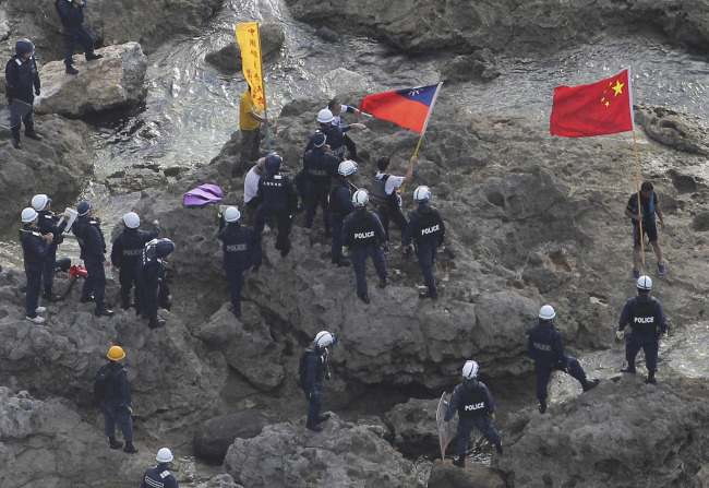 Activists holding Chinese and Taiwanese flags are arrested by Japanese police officers after landing on Uotsuri Island, one of the islands known as Senkaku in Japanese and Diaoyu in Chinese, in the East China Sea on Wednesday.   AP-Yonhap News