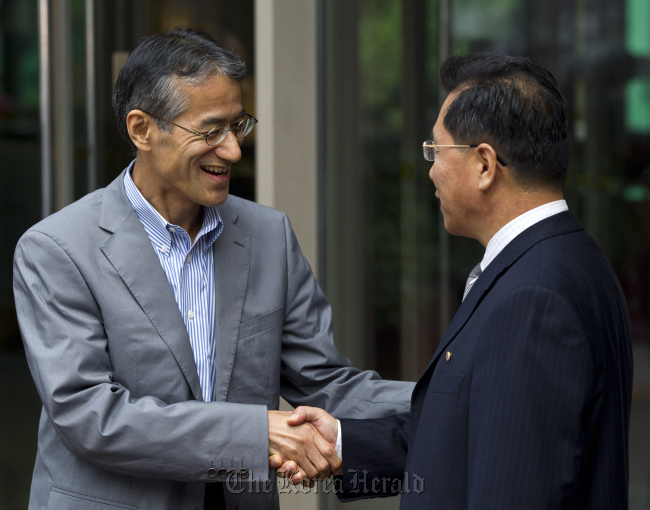 Ri Ho-rim (right) secretary general of North Korea's Red Cross Society, and Osamu Tasaka (left) director general of the International Department at the Japanese Red Cross, shake hands after a meeting in Beijing on Aug. 10. (AP-Yonhap News)