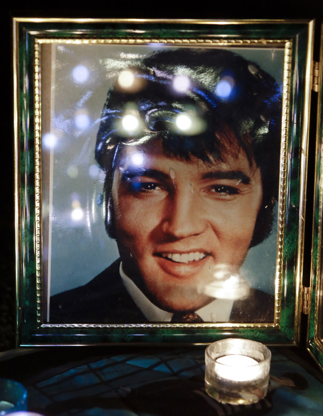 Candles are reflected in a photo of Elvis Presley at a memorial set up by a fan at a candlelight vigil at Graceland, Presley’s Memphis, Tennessee, home, on Wednesday. AP-Yonhap News