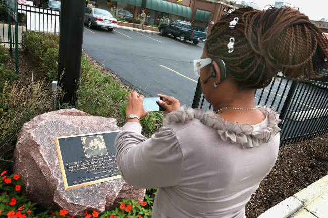 Cindee Towns takes a picture of a plaque placed outside a strip mall in the Hyde Park neighborhood that marks the location where President Barack Obama and first lady Michelle Obama shared their first kiss on Thursday in Chicago, Illinois.   AFP-Yonhap News