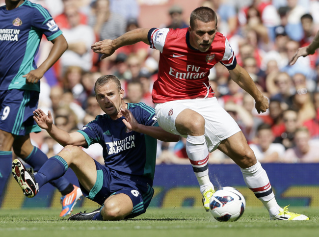 Arsenal’s Lukas Podolski (right) and Sunderland’s Lee Cattermole challenge for the ball on Saturday.   AP-Yonhap News
