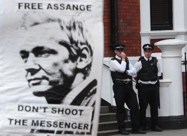 A supporter of Julian Assange holds a sign as police remain outside the Ecuadorian Embassy in London on Saturday.    AFP-Yonhap News