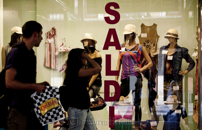 Shoppers pass a store advertising a sale in its window display in Rome.   Bloomberg