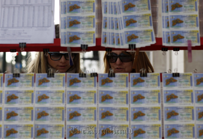 Customers look at state lottery tickets displayed for sale at a street vendor’s stand in Athens.    Bloomberg