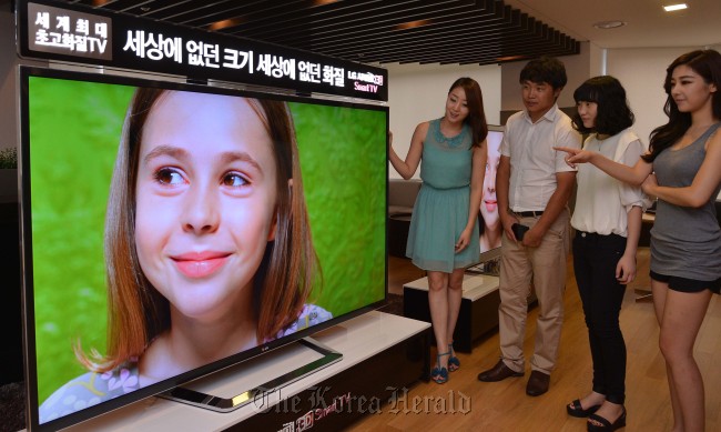 A group of people take a look at LG Electronics’ new ultra-high definition 3-D television, which is the world’s first, in Seoul on Wednesday.   Lee Sang-sub/The Korea Herald
