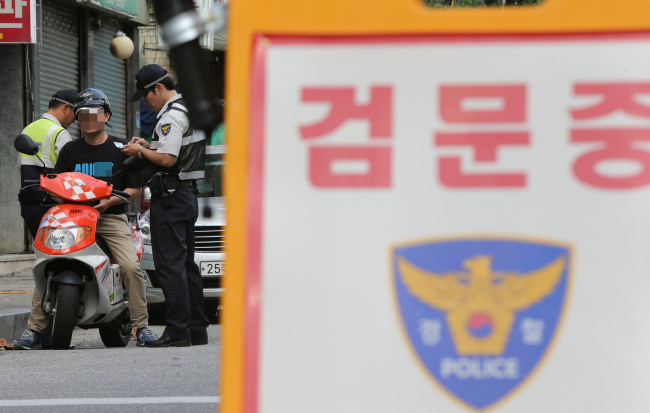<YONHAP PHOTO-0880> 경찰 불심검문 2년만에 부활 (서울=연합뉴스) 이정훈 기자 = 2일 오후 서울 영등포구 영등포시장역 인근에서 경찰관이 불심검문을 하고 있다. 이날 경찰청은 '묻지마' 범죄와 아동 성폭행 등 강력 범죄 예방을 위한 특별방범 활동 차원에서 이달부터 대로상에서 불심검문을 적극적으로 시행하라는 지침을 전국 지방경찰청과 경찰서에 내려 보냈다. 2012.9.2 uwg806@yna.co.kr/2012-09-02 16:06:51/Media Only <저작권자 ⓒ 1980-2012 ㈜연합뉴스. 무단 전재 재배포 금지.>
Police officers stop and question a person on a Seoul street on Sunday.   Yonhap News