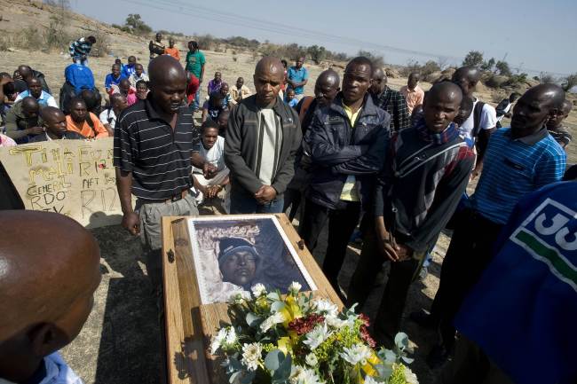 <YONHAP PHOTO-0025> TOPSHOTS..Mineworkers pray on August 31, 2012 over the coffin containing the body of Mpuzeni Ngxande, one of the 34 striking miners that were killed by police on August 16, in front of the rocky outcrop where the men were shot, an informal settlement near the Lonmin mine in Marikana, North-West Province. Talks to end a three-week strike at South Africa's Lonmin platinum mine, where violence claimed 44 lives, have been postponed to Monday after two days of negotiations failed to broker a deal. Mine managers, unions, workers representatives and government mediators are seeking a "peace accord" after the killing of 34 striking workers two weeks ago by police -- the worst day of police violence in South Africa since the end of white-minority apartheid rule in 1994. AFP PHOTO / RODGER BOSCH../2012-09-01 00:17:19/ <저작권자 ⓒ 1980-2012 ㈜연합뉴스. 무단 전재 재배포 금지.>
Mineworkers pray on Friday over the coffin containing the body of Mpuzeni Ngxande, one of the 34 striking miners that were killed by police on Aug. 16, in front of the rocky outcrop where the men were shot, an informal settlement near the Lonmin mine in Marikana, South Africa.   AFP-Yonhap News