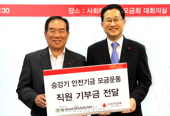 Kong Chang-seok (left), president of the Korea Elevator Safety Institute, poses with an official from the Community Chest of Korea after donating funds raised by the members of KESI, on Thursday in Seoul.   KESI