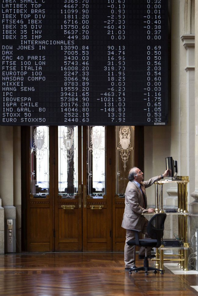 A visitor checks an electronic screen for stock price information inside the Madrid stock exchange, or Bolsas y Mercados, in Madrid.   Bloomberg