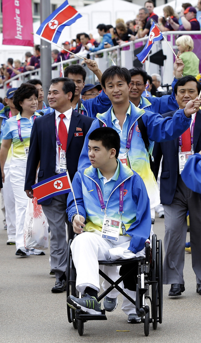 <YONHAP PHOTO-1813> In this Monday, Aug., 27, 2012 photo, North Korea's sole competitor Rim Ju Song, sits in his wheelchair during the team's welcoming ceremony at the London 2012 Paralympic games in London. Rim Ju Song, who actually lives in Beijing and lost an arm and leg in a construction accident, became his country's only hope. The problem: He couldn't really swim. The first training session was a disaster. He sank "like a rock," recalled Kim Sung Chol of the North Korean Paralympic Committee. Nevertheless, he soon learned the crawl stroke and in May, Rim and his coaches boarded a plane for Berlin and his first international competition. (AP Photo/Alastair Grant)/2012-08-28 20:05:09/ <저작권자 ⓒ 1980-2012 ㈜연합뉴스. 무단 전재 재배포 금지.>
North Korea’s sole competitor Rim Ju-song sits in his wheelchair during the team’s welcoming ceremony at the London 2012 Paralympic Games on Aug. 27.    AP-Yonhap News