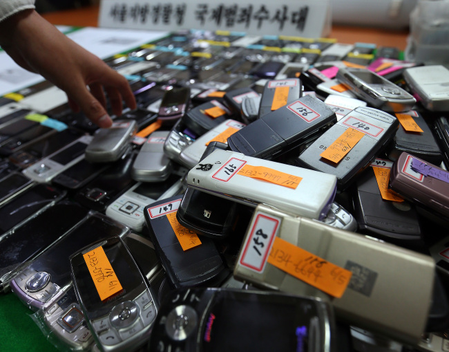 Mobile phones with forged identities of foreigners are on display at Gangnam Police Station in Seoul on Wednesday.   Yonhap News.