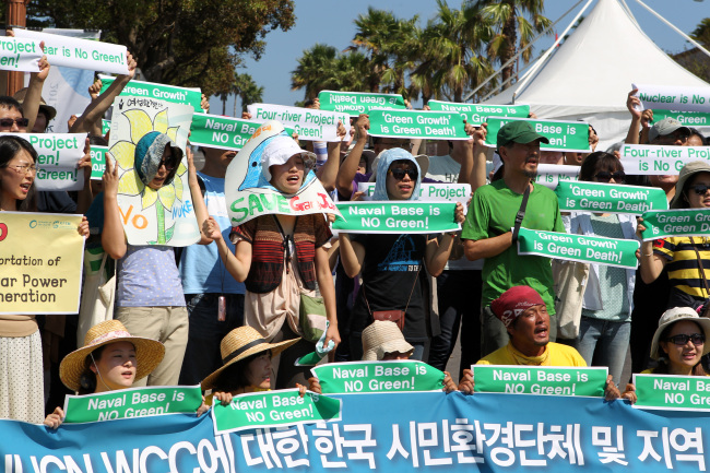 <YONHAP PHOTO-1427> '껍데기 환경총회' (서귀포=연합뉴스) 고성식 기자 = 6일 제주 세계자연보전총회가 개막한 서귀포 컨벤션센터 인근에서 한국환경회의 소속 회원들이 기자회견을 열고 '제주해군기지는 IUCN과 세계자연보전총회(WCC) 정신에 위배된다'고 밝히며 함성을 지르고 있다. 2012.9.6 koss@yna.co.kr/2012-09-06 15:33:29/ <저작권자 ⓒ 1980-2012 ㈜연합뉴스. 무단 전재 재배포 금지.>
Activists hold a rally on Thursday outside the Jeju Convention Center, where the World Conservation Congress is held, in protest against the Korean government’s ongoing construction of a naval base in Gangjeong, a small coastal village on the southern island.   Yonhap News