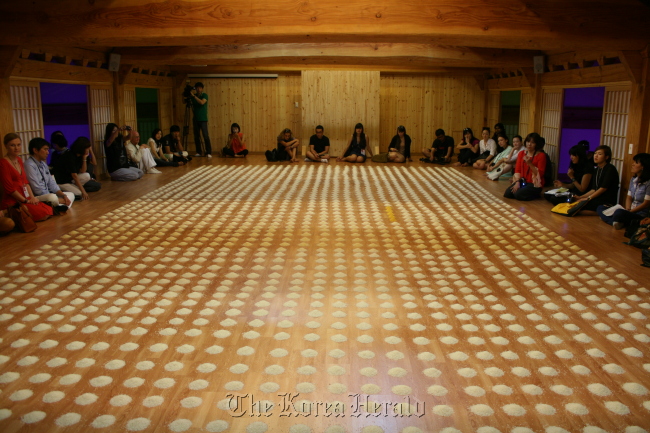 Viewers surround German artist Wolfgang Laib’s “Unlimited Ocean,” which consists of 25,000 piles of rice on a large wooden floor of the Buddhist temple Mugaksa in Gwangju.   Lee Woo-young/The Korea Herald