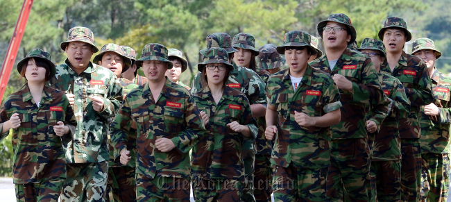 Wearing Marine uniforms, employees of Narae Nanotech run during a training camp operated by the private Marine Academy on Anmyeondo in South Chungcheong Province, on Thursday.   Ahn Hoon/The Korea Herald