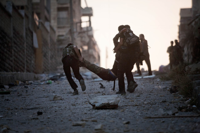 FSA soldiers help a severely wounded colleague after being shot by a Syrian Army sniper in Izaa district in Aleppo on Saturday.   AP-Yonhap News