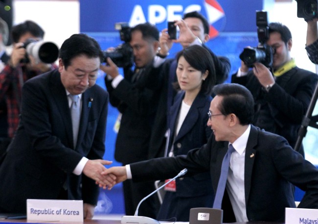 South Korean President Lee Myung-bak (right) shakes hands with Japanese Prime Minister Yoshihiko Noda as they attend the Asia-Pacific Economic Cooperation summit in Vladivostok, Russia, Sunday.   Yonhap News