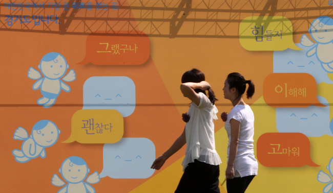 Participants walk in front of a panel written on with words of consolation during an event held at the Gyeonggi Provincial Government office to promote suicide prevention on Friday.   Yonhap News