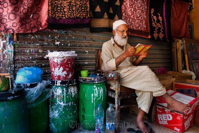 An employee at the block print shop sits next to barrels of dye used in the printing process.   Dawn