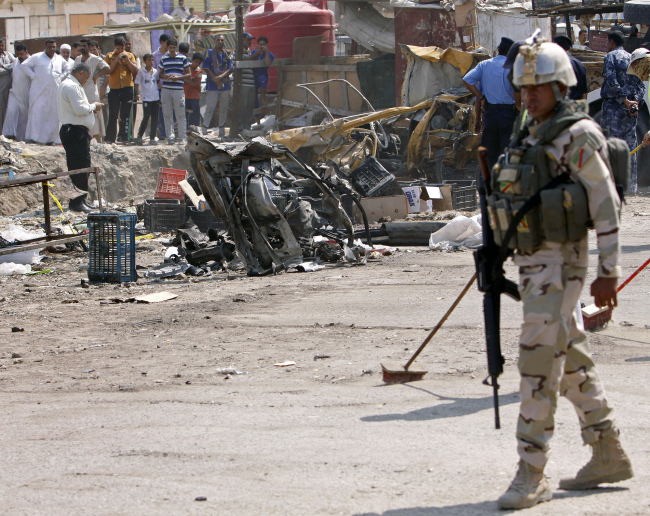 An Iraqi soldier stands guard as security forces inspect the scene of a car bomb attack in Basra, Iraq, Sunday.   AP-Yonhap News