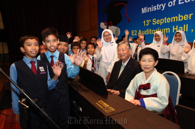 Booyoung Group chairman Lee Joong-keun and his wife Na Kil-soon pose for a photo with schoolchildren Thursday at the Education Ministry auditorium in Putrajaya, Malaysia.   Booyoung