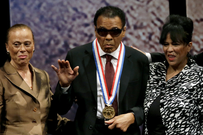 Retired boxing champion Muhammad Ali (center) waves alongside his wife Lonnie Ali (left) and his sister-in-law Marilyn Williams after receiving the Liberty Medal during a ceremony at the National Constitution Center in Philadelphia on Thursday.   AP-Yonhap News
