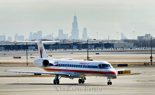 The skyline of Chicago stands behind an American Airlines aircraft at O’Hare International Airport in Chicago, Illinois.   Bloomberg