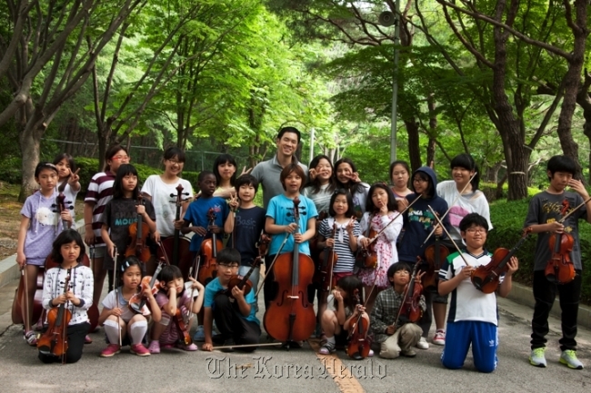 Violist Richard Yongjae O’Neill (center, back row) poses with the children appearing in “Hello?! Orchestra.”   CREDIA