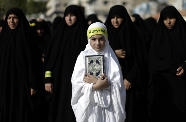 A Lebanese girl holds a copy of the Quran, the Muslim holy book, during a protest about a film ridiculing Islam’s Prophet Muhammad in the southern border town of Bint Jbeil, Lebanon, Saturday, for the latest in a series of protest rallies organized by the Shiite militant group Hezbollah. Arabic writing on her headband reads “at your service God’s Prophet.”   AP-Yonhap News
