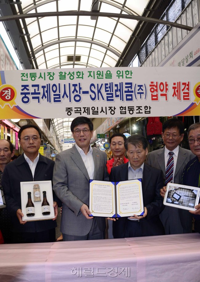 26일 오전 서울 광진구 중곡동 제일시장에서 하성민 SK텔레콤 사장과 상인협동조합 박태신 이사장들이 참석한 가운데 Myshop등 ICT 솔루션, 전문가 교육,공공 마케팅 활동 등 전통시장 혁신프로그램을 지원하는 '중곡 제일시장 활성화를 위한 업무협약식'을 맺고 있다. 박해묵 기자/mook@heraldcorp.com
26일 오전 서울 광진구 중곡동 제일시장에서 하성민 SK텔레콤 사장과 상인협동조합 박태신 이사장들이 참석한 가운데 Myshop등 ICT 솔루션, 전문가 교육,공공 마케팅 활동 등 전통시장 혁신프로그램을 지원하는 '중곡 제일시장 활성화를 위한 업무협약식'을 맺고 있다. 박해묵 기자/mook@heraldcorp.com
하성민 SK텔레콤 사장(왼쪽에서 두번째)이 26일 서울 광진구 중곡동 제일시장에서 ‘중곡 제일시장 활성화를 위한 업무협약식’을 체결한 후 상인들과 기념 촬영을 하고 있다.    박해묵 기자/mook@