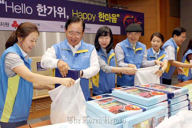 Shinhan Financial Group chairman Han Dong-woo (second from left) helps pack gift sets to be delivered to poor children across the nation at the lender’s headquarters last week.
Shinhan Financial Group