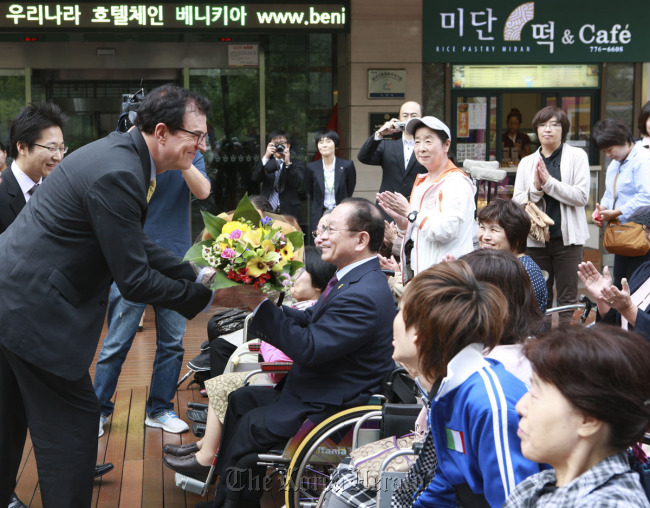 Lee Charm (left), CEO of The Korea Tourism Organization, shakes hands with a Japanese tourist in Seoul on Wednesday.   The Korea Tourism Organization