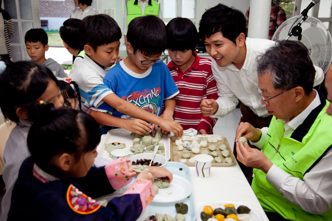 KEB CEO and KEB Foundation chairman Yun Yong-ro (right) makes songpyeon with children at a social welfare center in Seoul on Tuesday.   KEB