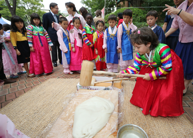 A school girl in hanbok pounds a slab of rice dough in preparation for making Chuseok rice cakes at the French School of Seoul in Seorae Village, Seoul, last Friday.   Yonhap News