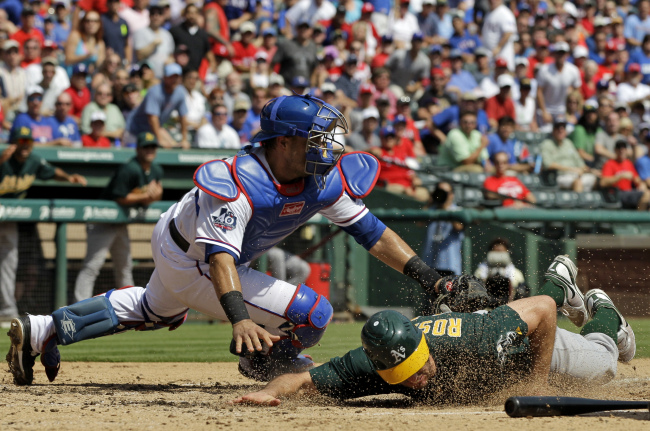 Oakland Athletics’ Adam Rosales scores at under the attempted tag by Texas Rangers’ Geovany Soto during the third inning of a baseball game in Arlington, Texas, Thursday.   AP-Yonhap News