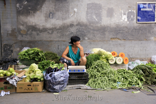 A vegetable vendor waits for customers in a hutong, Beijing.   Bloomberg