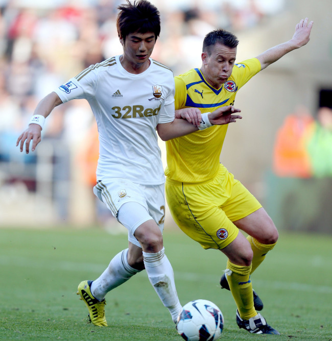 Swansea City’s Ki Sung-yueng (left) and Reading’s Nicky Shorey challenge for the ball on Saturday. The match ended in a 2-2 draw.   AP-Yonhap News
