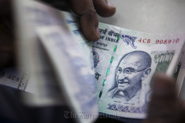 A cashier counts Indian 100-rupee banknotes at an Oriental Bank of Commerce branch in New Delhion Sunday.   Bloomberg