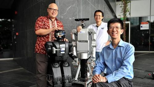 Scientists making better robots include (from left) Han Boon Siew with his black robot Hubo, Tee Keng Peng with his Meka Robot, and Li Haizhou, the department head and principal scientist of the Human Language Technology Department, at A*Star’s Institute for Infocomm Research.   The Straits Times