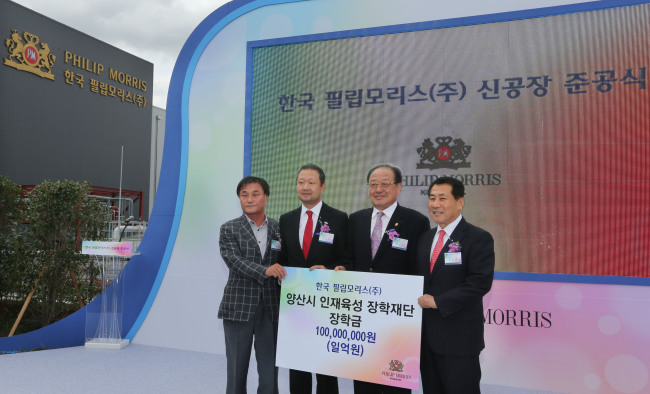 Chong Il-woo (second from left), managing director of PMKI, delivers 100 million won in scholarship funds to a charity foundation during the opening ceremony for its new plant in Yangsan, South Gyeongsang Province, Monday.   Philip Morris Korea