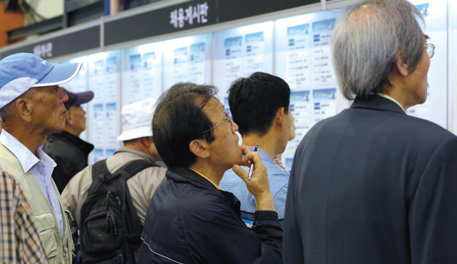 Job seekers look through openings at a job fair for over-55s in Seoul on Sept. 25. Yonhap News