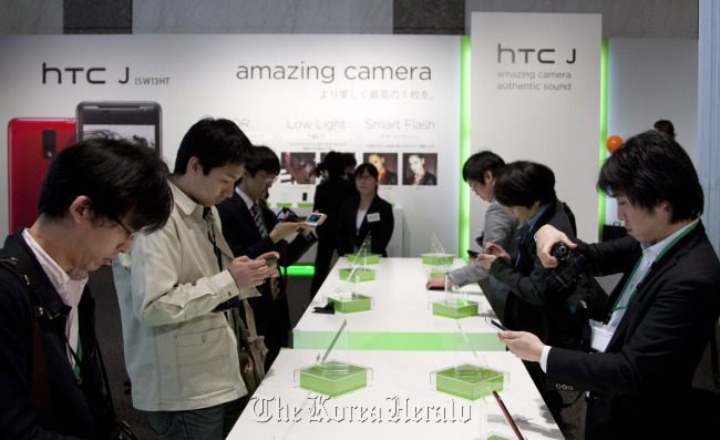 Members of the media try HTC J smartphones at its unveiling held by HTC Corp. and KDDI Corp. in Tokyo.   Bloomberg