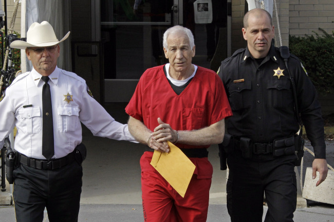 Jerry Sandusky (center) is escorted by police after being sentenced on Tuesday.   AP-Yonhap News