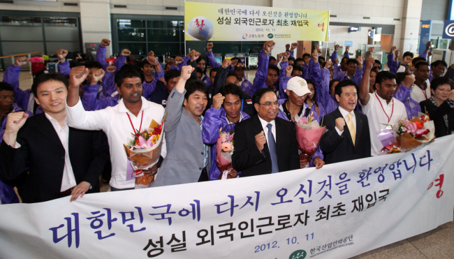 Foreign workers with re-employment permits and Seoul officials pose during a welcoming ceremony at Incheon International Airport on Thursday.   Yonhap News