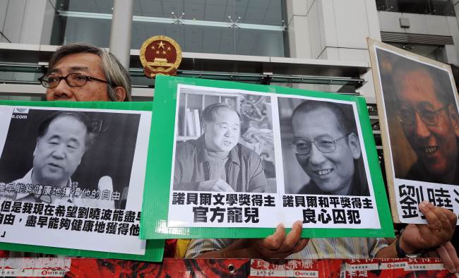 Protesters hold pictures of Chinese writer Mo Yan (left) and Chinese dissident Liu Xiaobo (right) during a demonstration in front of the Chinese liaison offices in Hong Kong on Saturday.   AFP-Yonhap News
