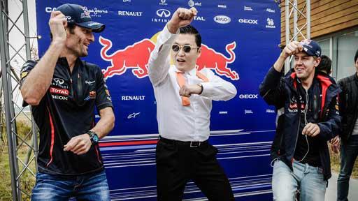 Korean singer Psy is doing the famous "horse-riding dance" with Mark Webber of Australia (left) and Red Bull-Renault driver Sebastian Vettel of Germany (right). (AFP)