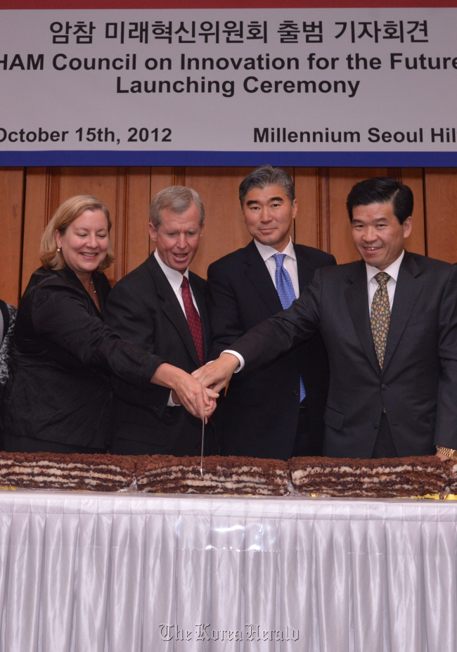 (From left) AMCHAM Korea President Amy Jackson, AMCHAM Korea chairman Pat Gaines, U.S. Ambassador Sung Kim, and James Kim, general manager and CEO of Microsoft Korea and inaugural chairman of the AMCHAM Council on Innovation for the Future, cut rice cakes at the council’s launch in a Seoul hotel on Monday.   Lee Sang-sub/ The Korea Herald