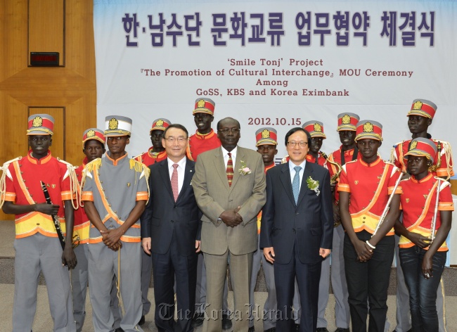 KBS president Kim In-kyu (third from left, front row), South Sudan’s Information Minister Barnaba Marial Benjamin (center) and Korea Eximbank CEO Kim Yong-hwan (fifth from left, front row) pose with a teenage brass band from the South Sudanese village of Tonj at KBS headquarters in Seoul on Monday.   Korea Eximbank