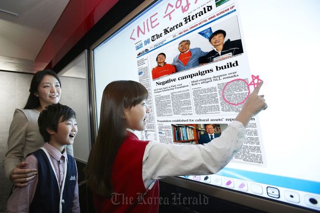 Two school students learn English through a newspaper In education program, using LG Display’s new electronic chalkboard made with the company’s 84-inch ultra definition liquid-crystal display at a ceremony in Seoul, Wednesday.   LG Display