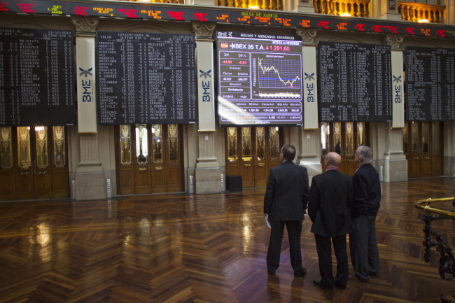 Visitors stand and look up at Ibex stock price information displayed on screens inside the Madrid Stock Exchange, or Bolsa y Mercado, in Madrid, Spain, on Thursday, Oct, 11, 2012. Spanish government bonds are facing a selloff by investors concerned that the nation's credit rating will be cut to non-investment grade after Standard & Poor's lowered its ranking for the debt to one level above junk. Photographer: Angel Navarrete/Bloomberg
Visitors look at screens inside the Madrid Stock Exchange.   Bloomberg