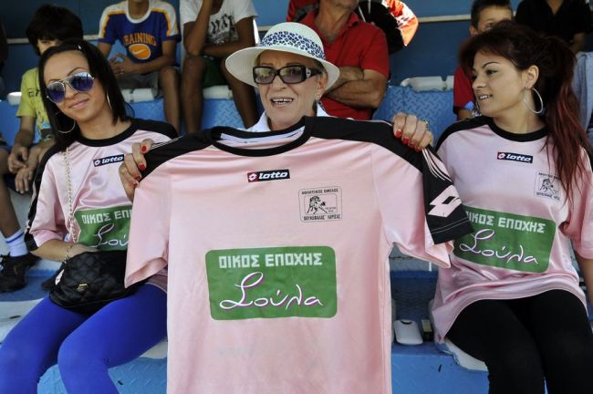 Brothel owner Soula Alevridou, centre, the benefactor of the Voukefalas amateur soccer team, holds up their new jersey for photographers, during a local championship match, in the city of Larissa, central Greece. (AP)